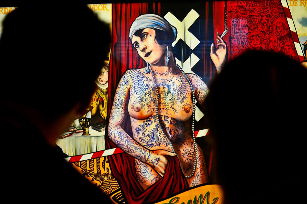 Pareja mirando mural mujer tatuajes rebelde fumando marihuana Amsterdams Historich Museum